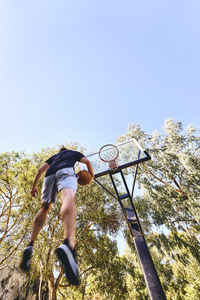 Full length of man playing basketball against trees