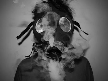 Close-up of man wearing gas mask against wall