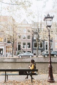 Rear view of woman sitting on bench in city