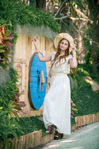 Portrait of smiling young woman standing against plants