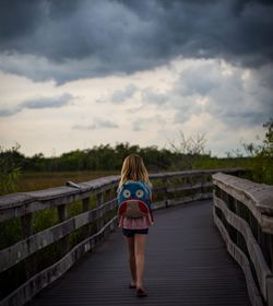 Full length of woman standing on road against cloudy sky