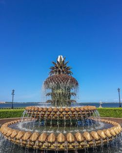 Pineapple fountain at waterfront park against clear blue sky