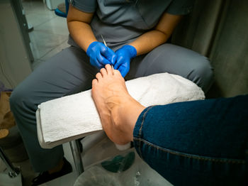 Gloved master makes a pedicure for a client. close-up no face. woman in nail salon