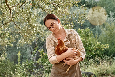 Woman holding brown hen in her hands. free-grazing domestic hen in free range poultry farm.