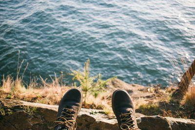 Low section of person wearing shoes against sea