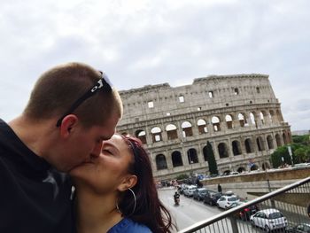 Close-up of couple kissing against coliseum