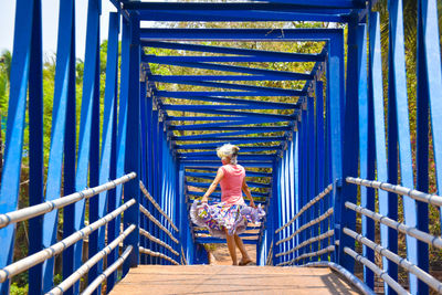 Woman standing against blue bridge