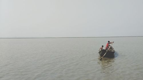 People enjoying in sea against clear sky