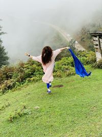 Rear view of woman with arms raised on field