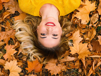 Portrait of woman lying on leaves during autumn