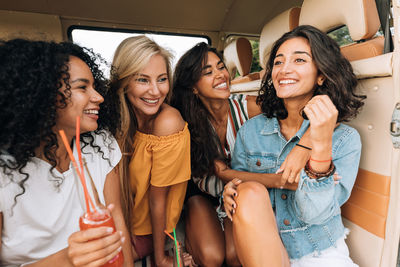 Happy friends sitting in car