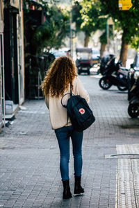 Full length rear view of woman standing on footpath