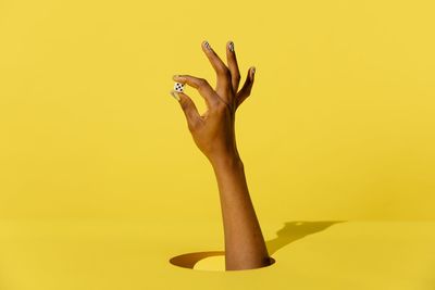 Close-up of woman hand against yellow background