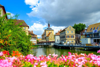 View of buildings by river against cloudy sky