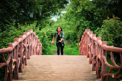 Portrait of smiling woman running on footbridge