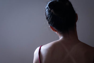 Rear view of shirtless woman against gray background
