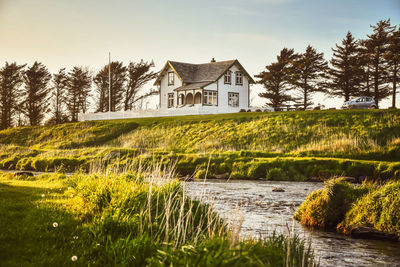 House by lake against sky