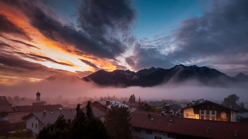 Panoramic view of buildings and mountains against sky during sunset