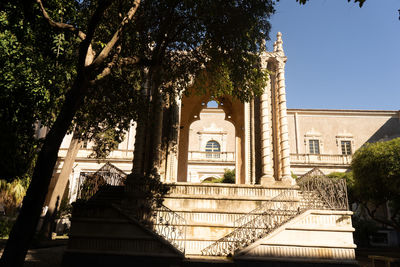 Low angle view of trees and building against sky