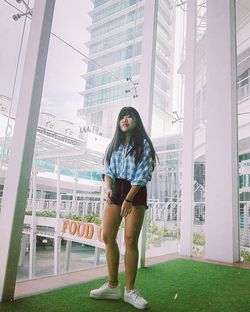 Portrait of young woman standing against building in city