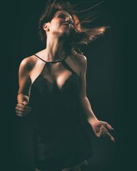 Midsection of woman standing against black background