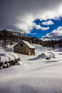 Snow covered landscape and houses against sky