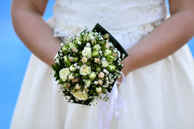 Midsection of bride holding flower bouquet