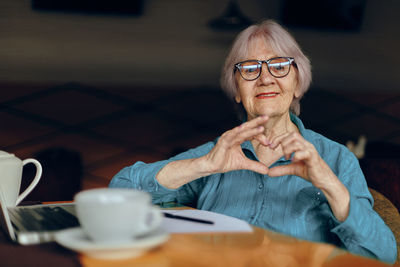 Portrait of senior woman wearing eyeglasses gesturing at cafe