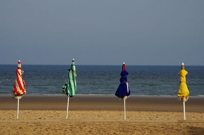 Deck chairs on beach against clear sky