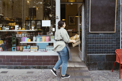 Female owner walking inside store holding crate