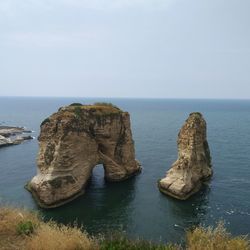 Rock formation in sea against clear sky