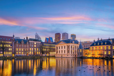 Buildings by river against sky