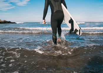 Low section of person on beach against sky