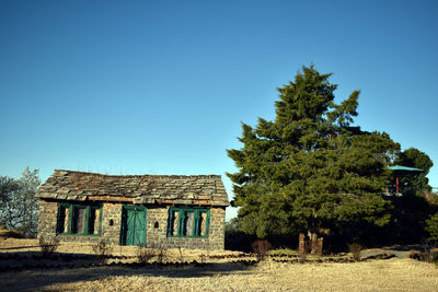 Abandoned house on field against clear blue sky