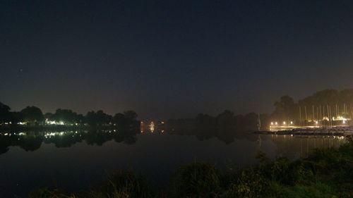 Reflection of illuminated trees in calm lake at night