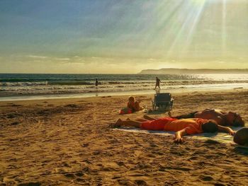 People relaxing on beach against sky