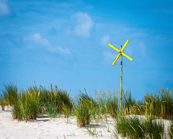 Low angle view of wind turbines on field against sky