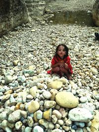 Portrait of girl crouching on pebbles