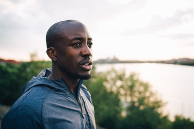 Sportsman looking away while standing on hill against sky