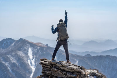 Rear view of man standing on mountain against sky