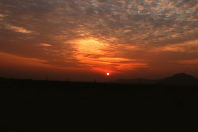 Scenic view of silhouette landscape against dramatic sky during sunset