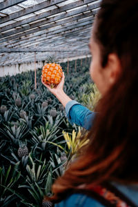 Side view of woman holding a pineapple