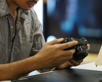 Midsection of man using camera at table