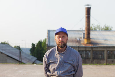 Portrait of manual worker standing against industrial building