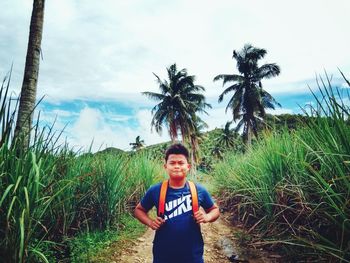 Portrait of smiling young man standing on field against sky