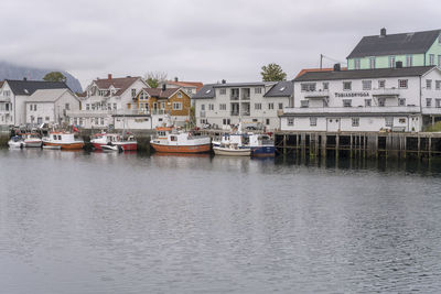 Houses by river against buildings in city