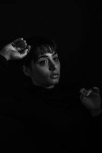 Close-up of thoughtful young woman against black background