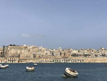 Sailboats in sea against buildings in city