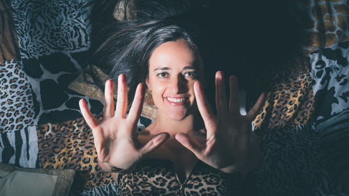 High angle portrait of woman gesturing while lying on bed