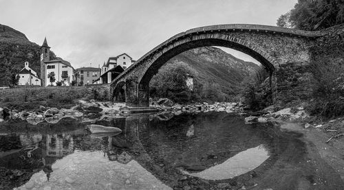 Arch bridge over river against buildings